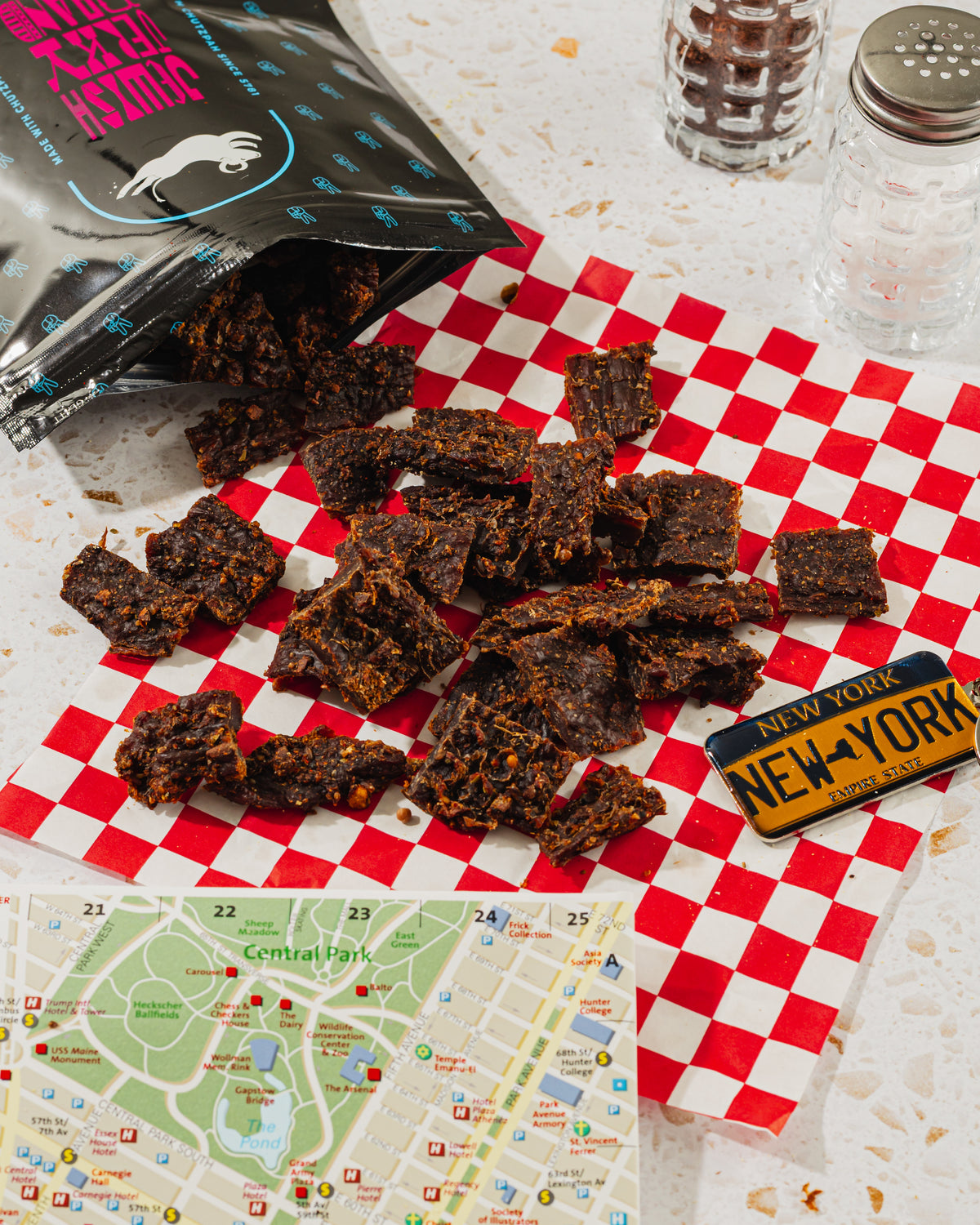 Pastrami Style jerky with deli accompaniments on red checkered paper